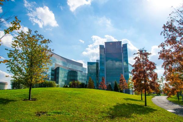 A landscape of a clean, glass building, over rolling, green hills.