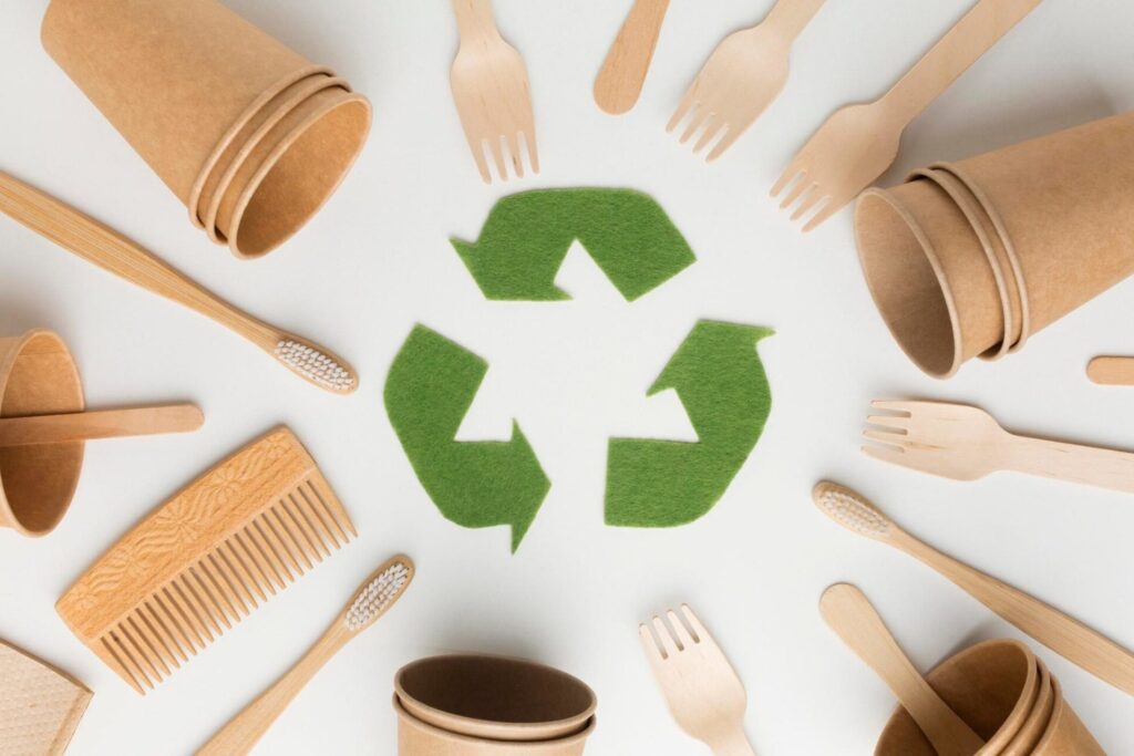 Sustainable utensils, all aligned towards the center where a green recycling logo sits.